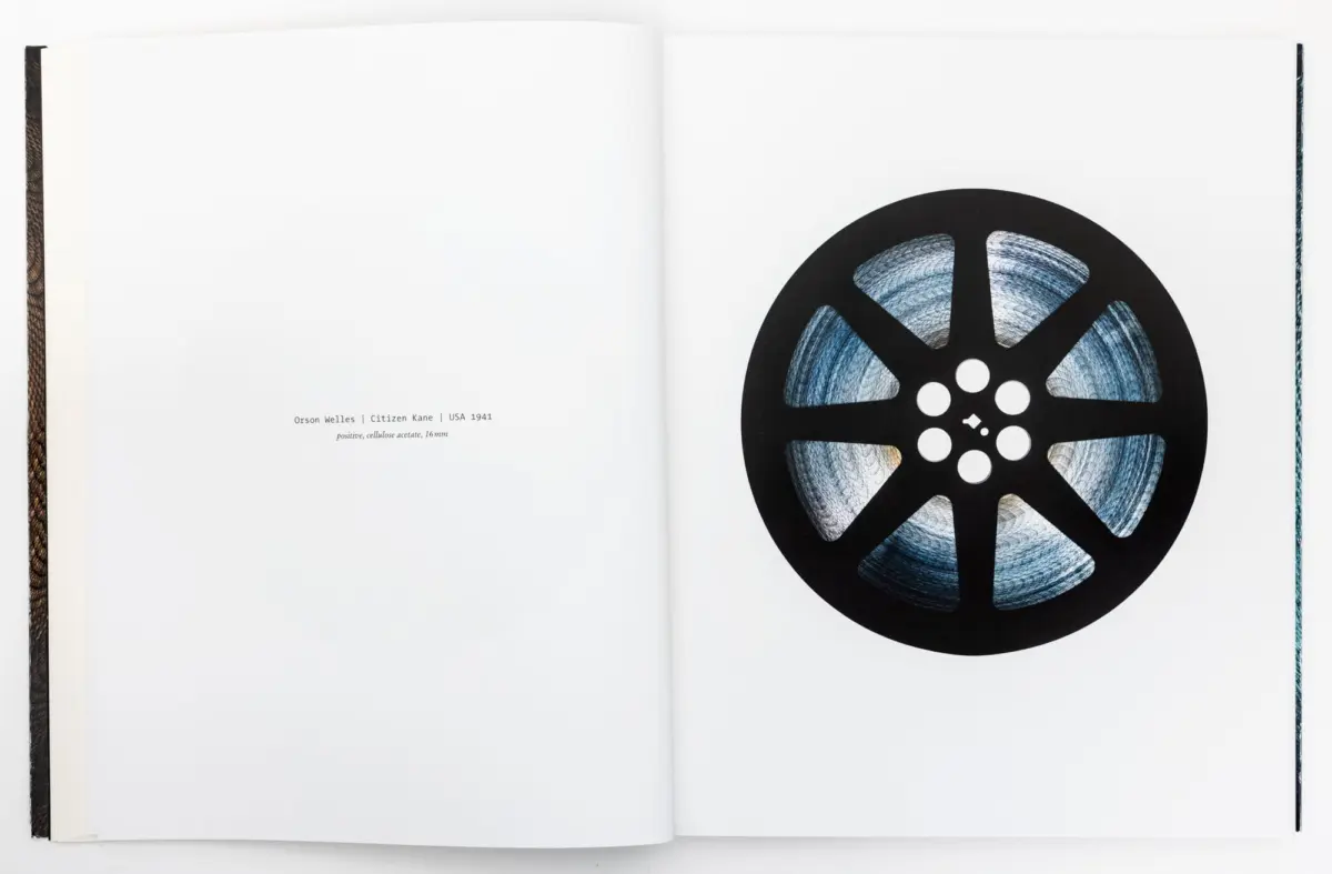Open book spread with a large black film reel on the right page; left page contains a small caption.