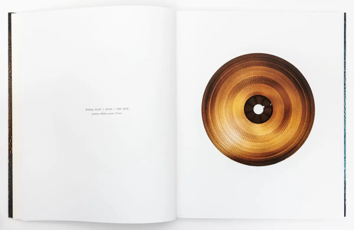 Open book with a large woven rattan disc on the right page, resting on white pages; left page is largely blank.