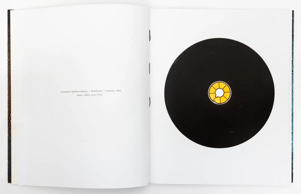 Open book spread featuring a large black vinyl record on the right page.