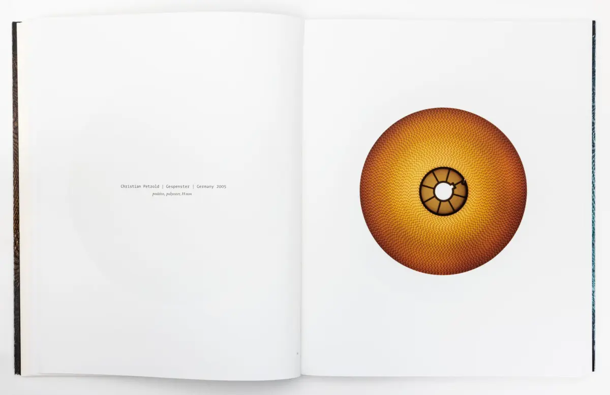Open art book showing a large orange torus sculpture with a honeycomb texture on the right page.