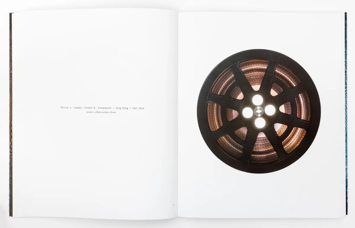 Open book spread with a large black film reel on the right page.