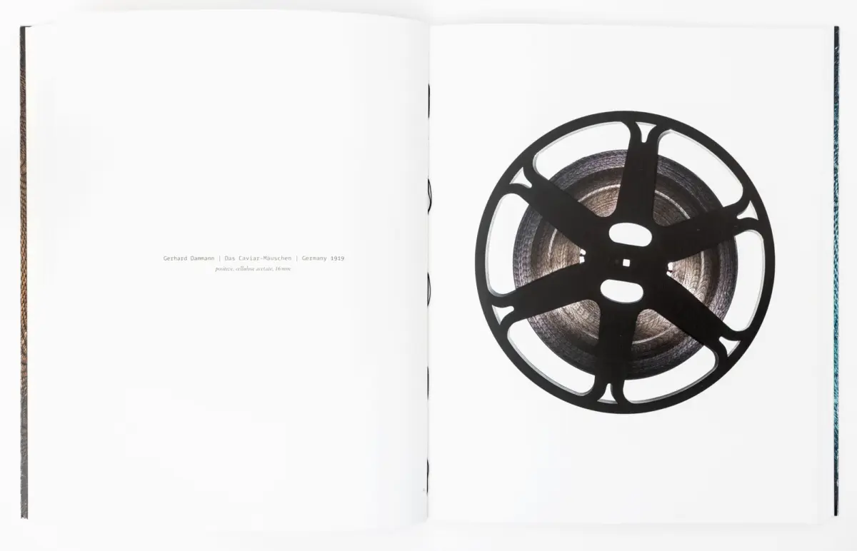 Open book spread with a large film reel illustration on the right page; left page largely blank.