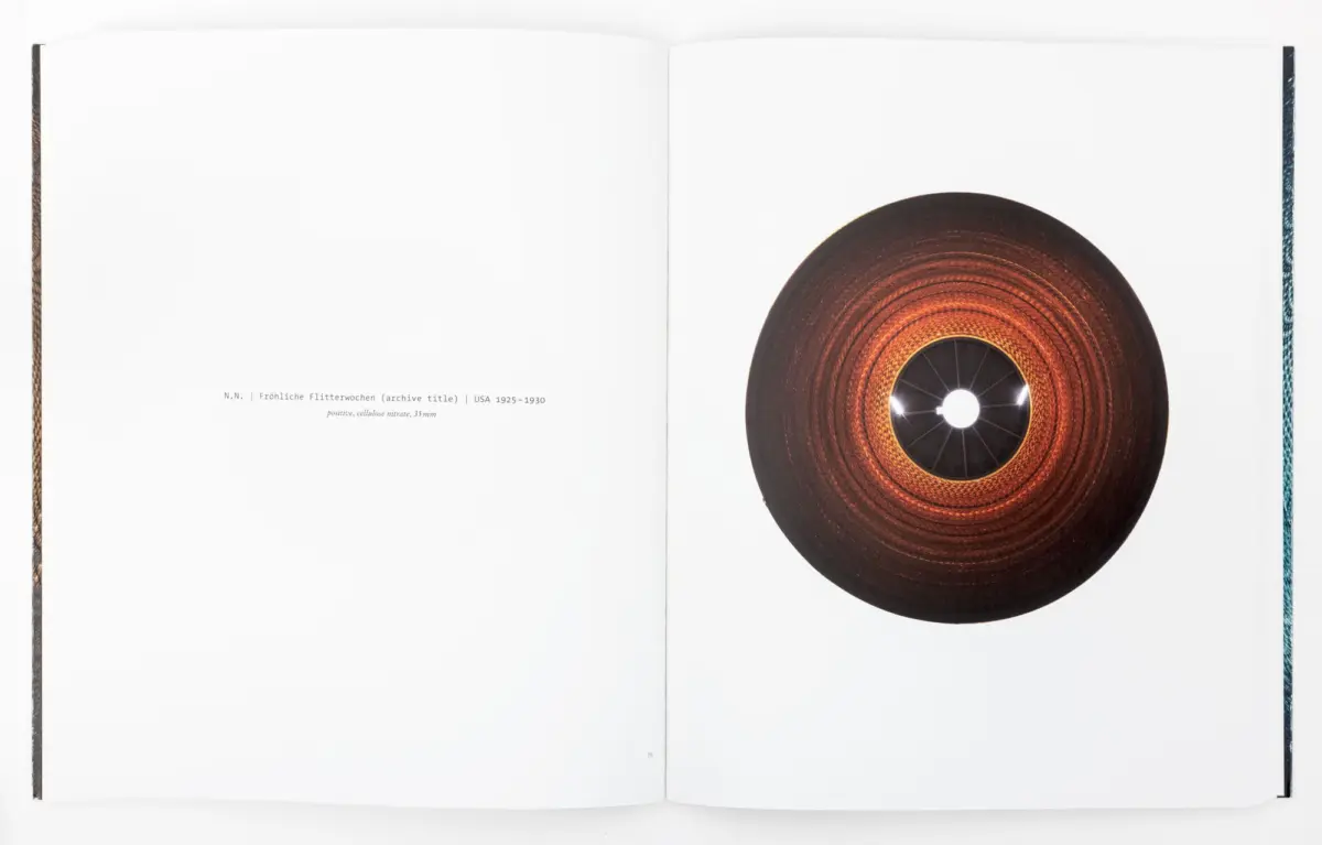 Open book spread; right page shows a large orange-brown circular disk with a central hole, left page blank.