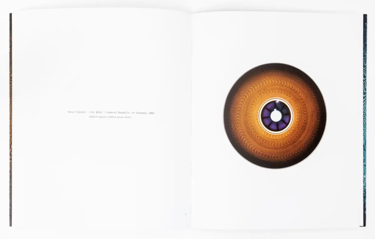 Open book spread on a white background; right page shows a large orange-brown circular disc with a purple center, left page largely blank.