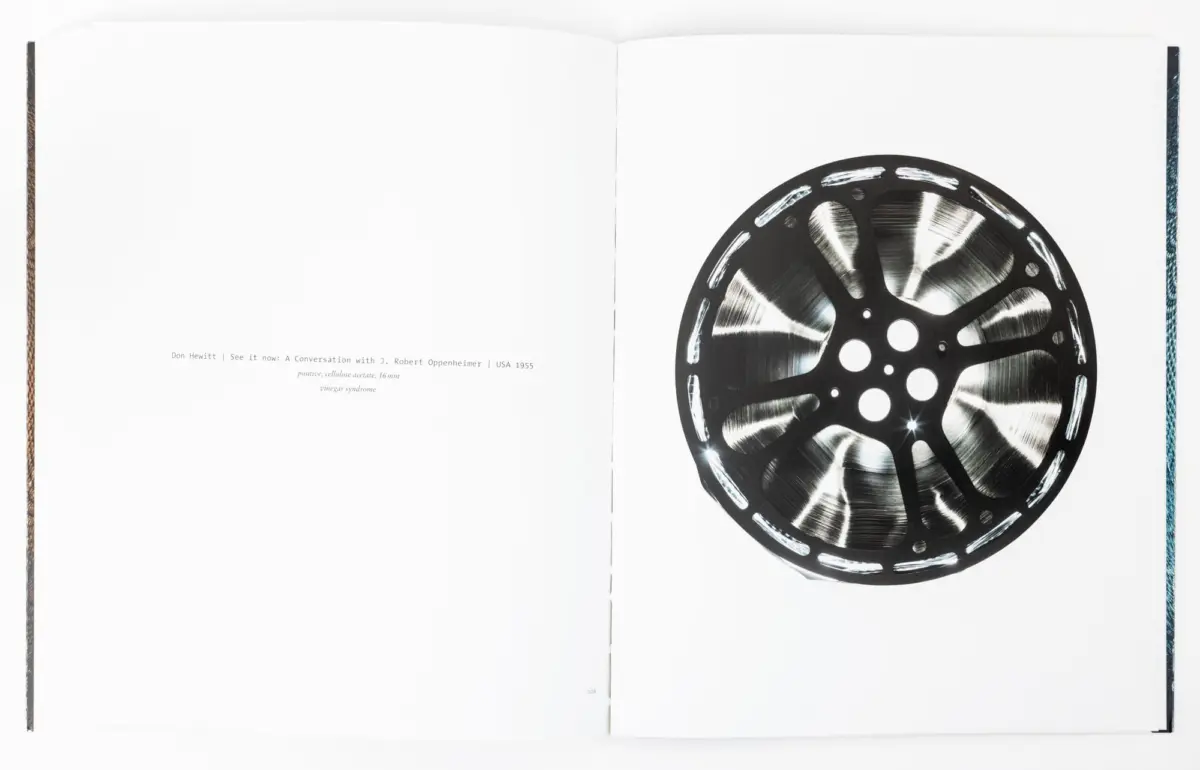 Open book spread with a large film reel on the right page; left page blank, book binding visible along the margins.