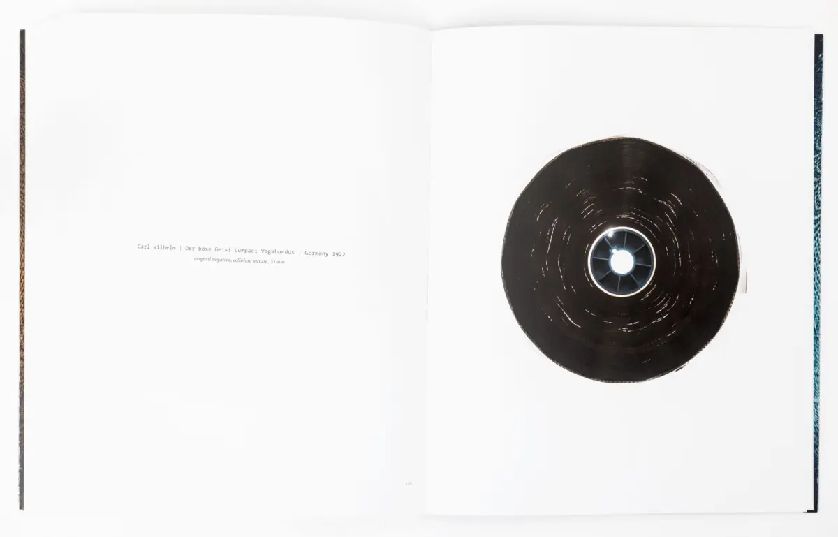 Open book with white pages; a black vinyl record rests on the right page of the spread.
