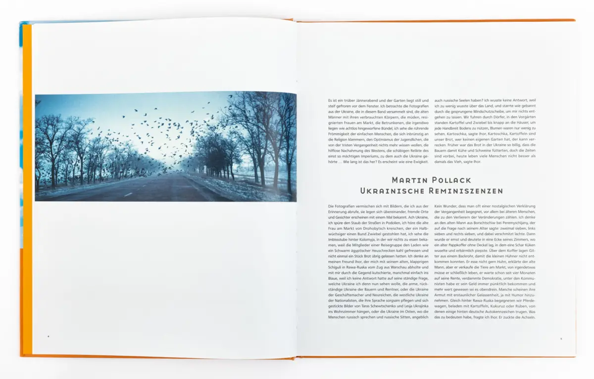 Open book spread: blue-toned photo of a road lined by bare trees with a flock of birds; right page contains German text.