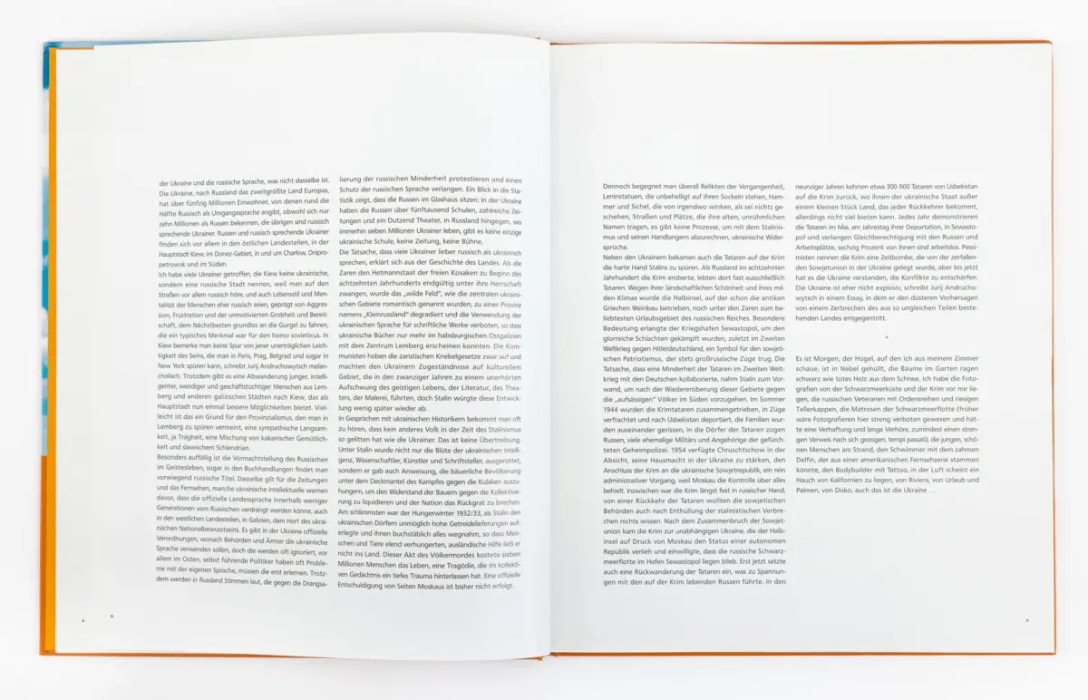 Open book with a two-page spread of dense German text, orange binding, on a white surface.