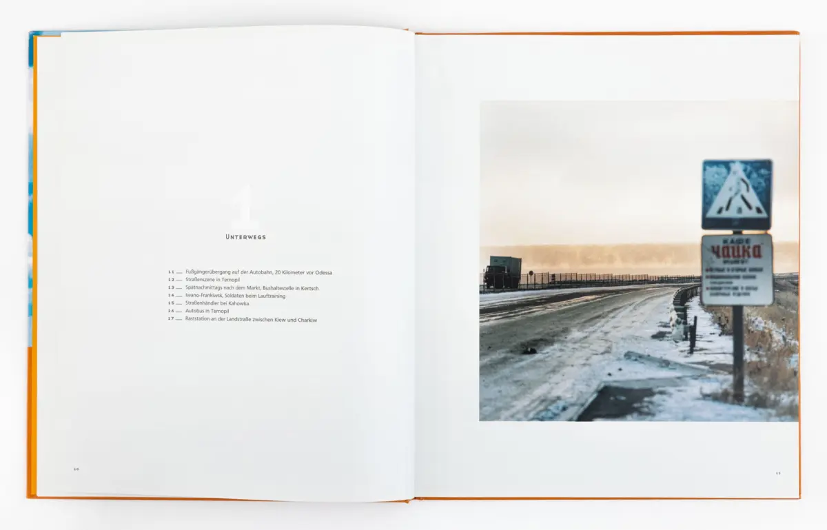 Open book; left page shows 1 Unterwegs contents, right page features a snowy highway with road signs and guardrail.