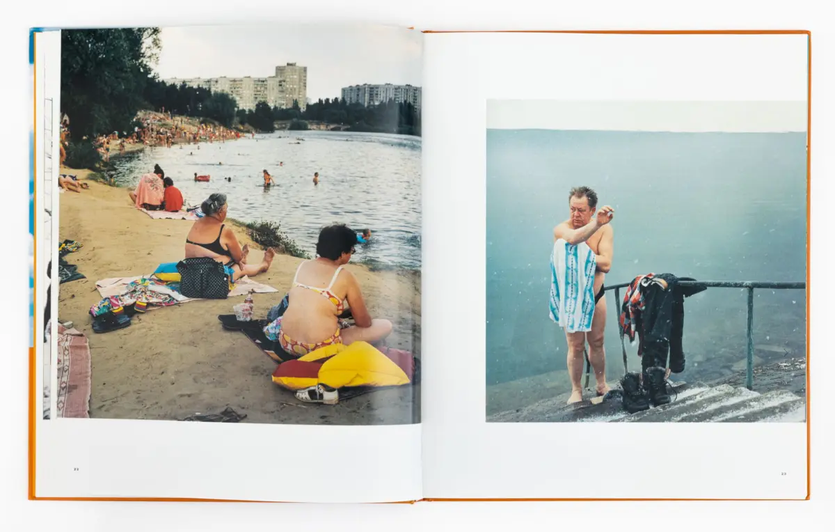 Two-page spread: left, crowded beach with sunbathers and swimmers; right, man drying off with towel on railing by water.