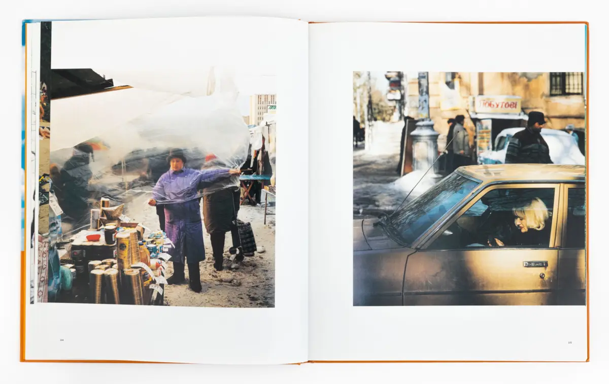 Open book spread: left page shows a street market vendor under plastic sheeting amid cans; right page shows a gold sedan with a blonde woman inside.
