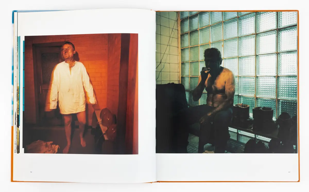 Open book with two photos: left, man in white shirt in orange doorway; right, shirtless man sitting and smoking near glass-block wall.