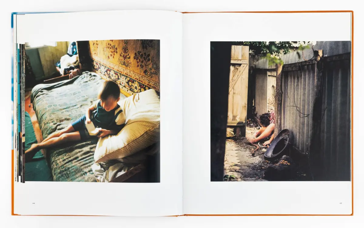 Two-page spread: left, a child sits on a bed reading beside a patterned rug; right, a person by a wooden fence in a yard.