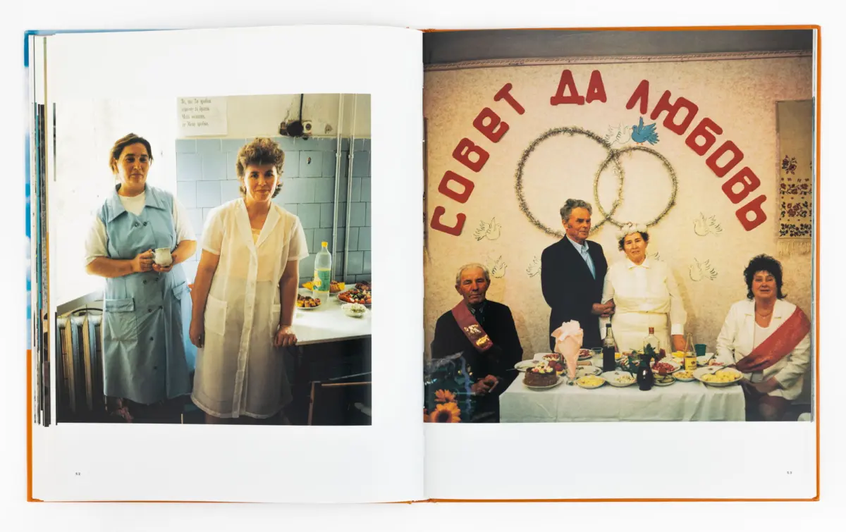 Open photo book spread: left image shows two women in a kitchen with food on a counter; right image shows guests at a decorated banquet.