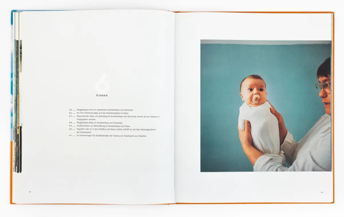 Infant with pacifier being held by an adult against a blue background on an open two-page magazine spread.
