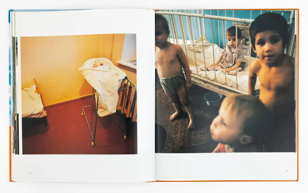 Open book; left page shows a newborn infant in a hospital bassinet; right page shows several young children in a ward with metal cribs.