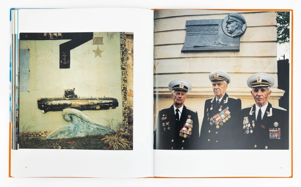 Open book spread; right page shows a stone relief bust of a military officer above three medal-clad naval officers; left page shows a weathered wall.