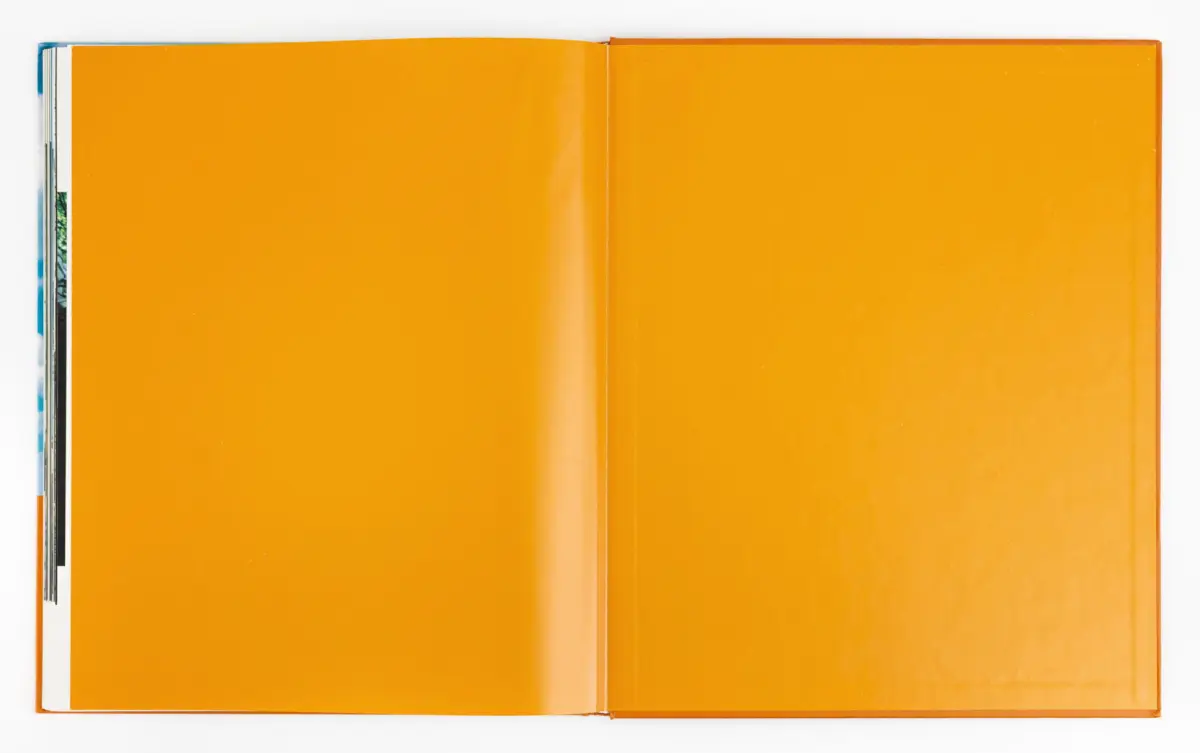 Open book with bright orange pages, spread on a white surface.