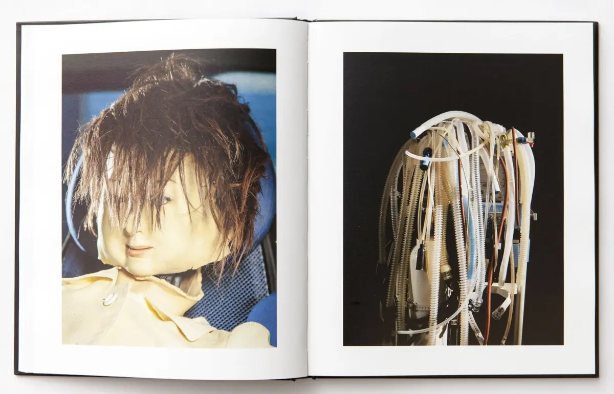Open book displaying: left a disheveled mannequin head; right a tangle of anesthesia tubes and equipment.