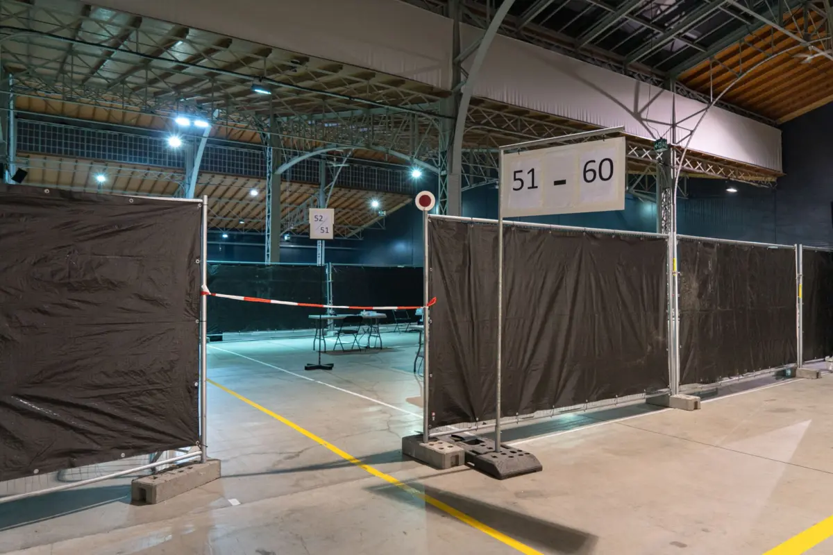 Empty indoor exhibition hall with black partitioned booths and signs reading 51-60.