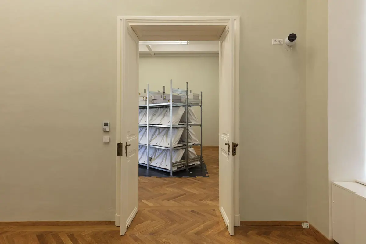 Open double doors to a storage room with metal shelving and fabric-wrapped bundles.