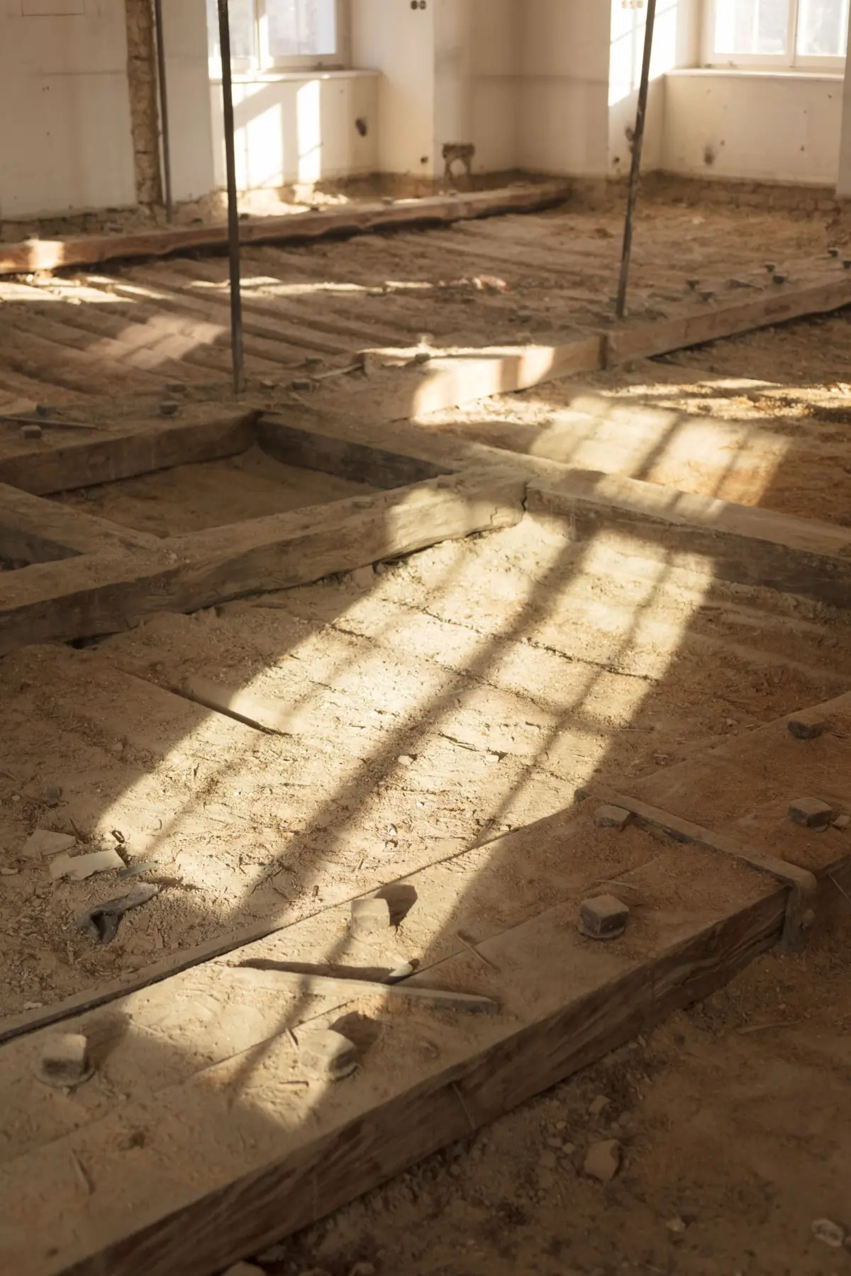 Interior of a construction site showing dug trenches, wooden formwork, and metal poles under sunlight.