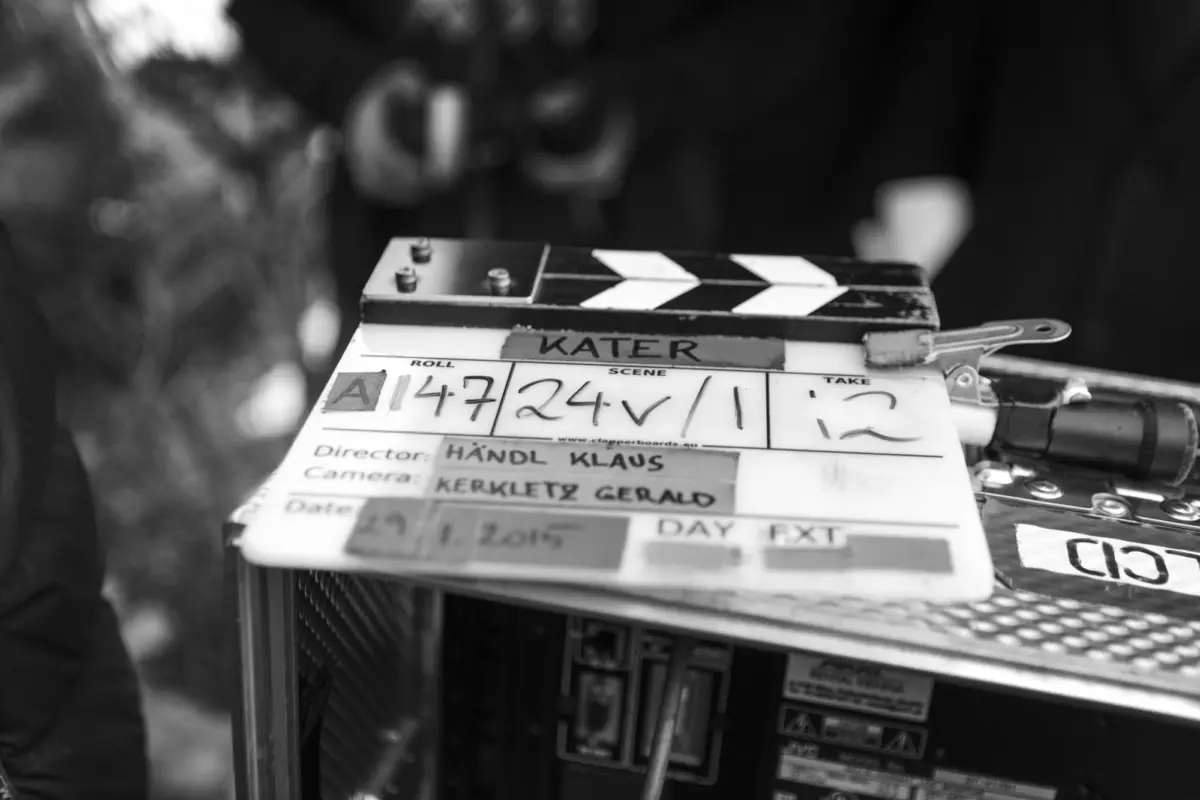 Black-and-white clapperboard resting on a camera rig at a film set.