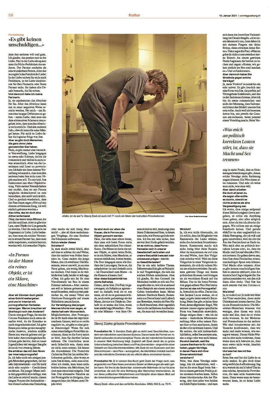 Adult man in a gray t-shirt and jeans bent over in a small bathroom, holding his head beside a toilet, looking distressed.
