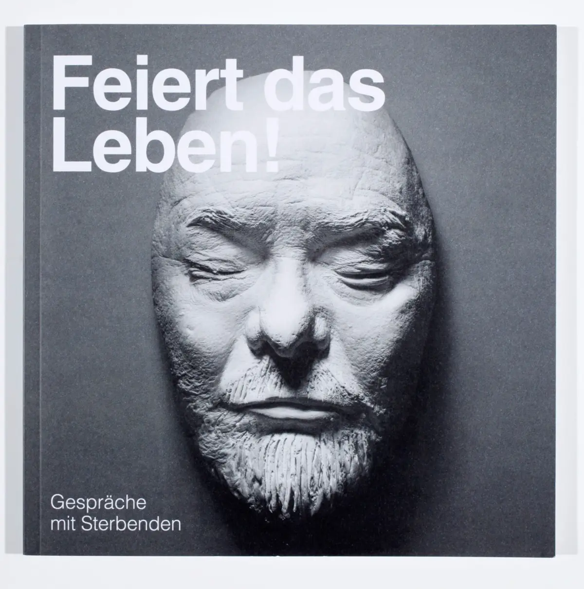 Grayscale magazine cover featuring a close-up of an elderly man's face; bold white headline 'Feiert das Leben!' on a dark background