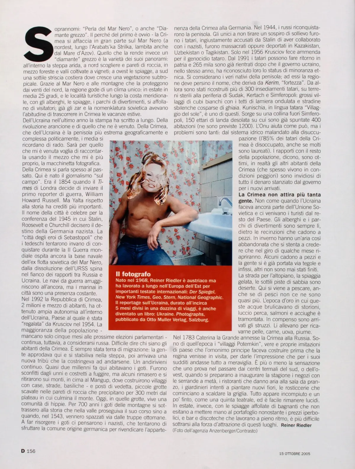 Shirtless man with long blond hair leaning on the edge of a bathtub in a bathroom with floral wallpaper.