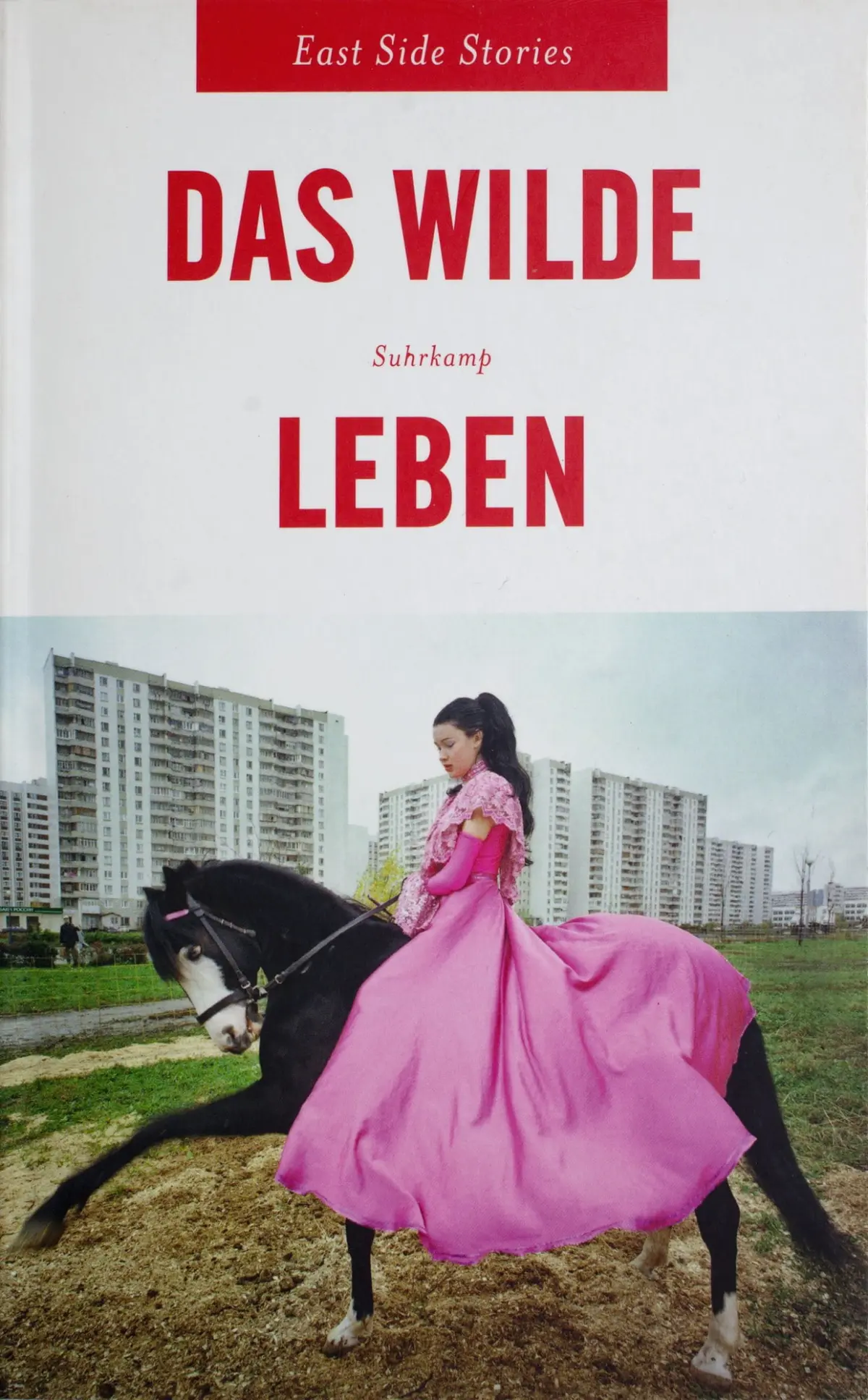 Book cover: person in a pink ball gown riding a black horse across a dirt lot with high-rise apartment buildings in the background.
