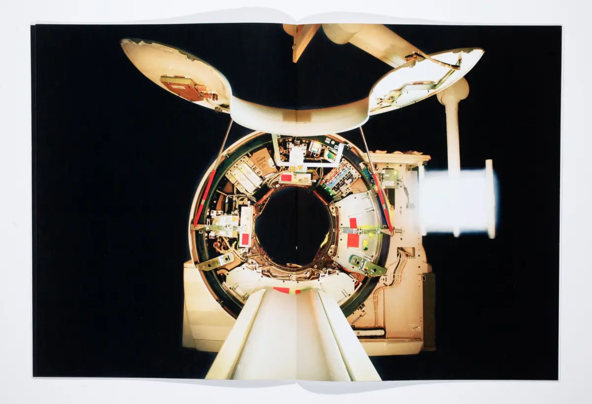 Exposed circular spacecraft ring with internal electronics and wiring, supported by white struts against a dark background.
