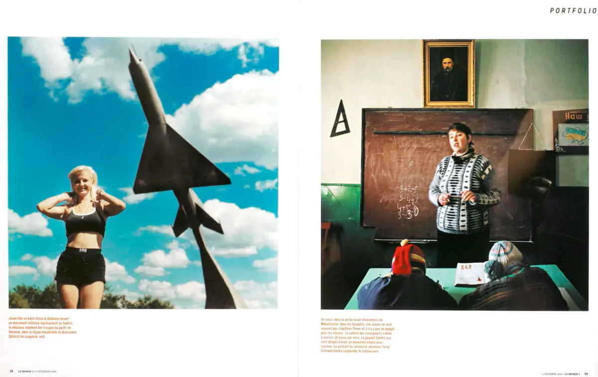 Person with blonde hair in a black sports bra and shorts stands outdoors beside a tall fighter-jet sculpture under a blue sky.
Teacher in a black-and-white striped cardigan stands by a chalkboard teaching math in a classroom, students wearing knit hats.