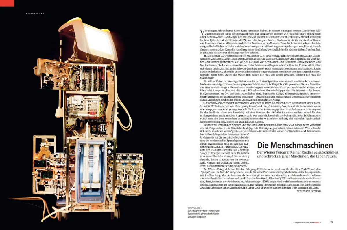 Tall vintage device with exposed circuitry and cables, glowing screen at the top, viewed against a dark background.