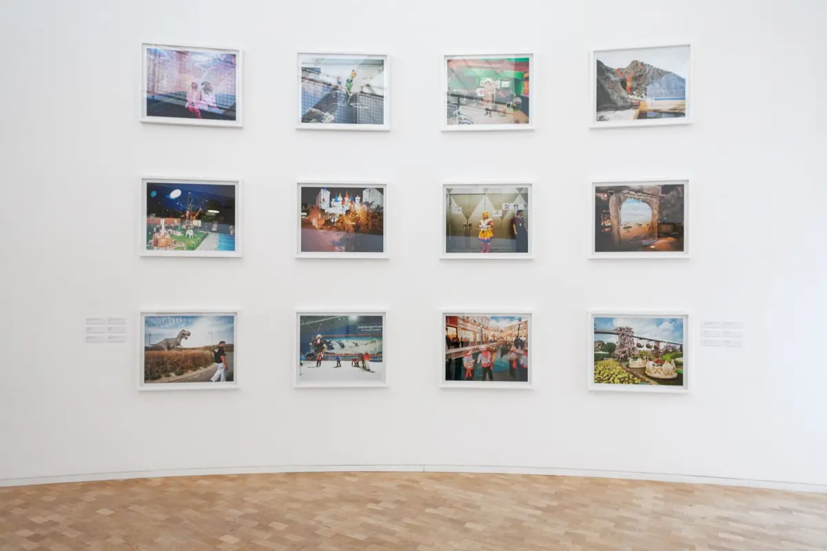 Framed photographs arranged in a grid on a white gallery wall.