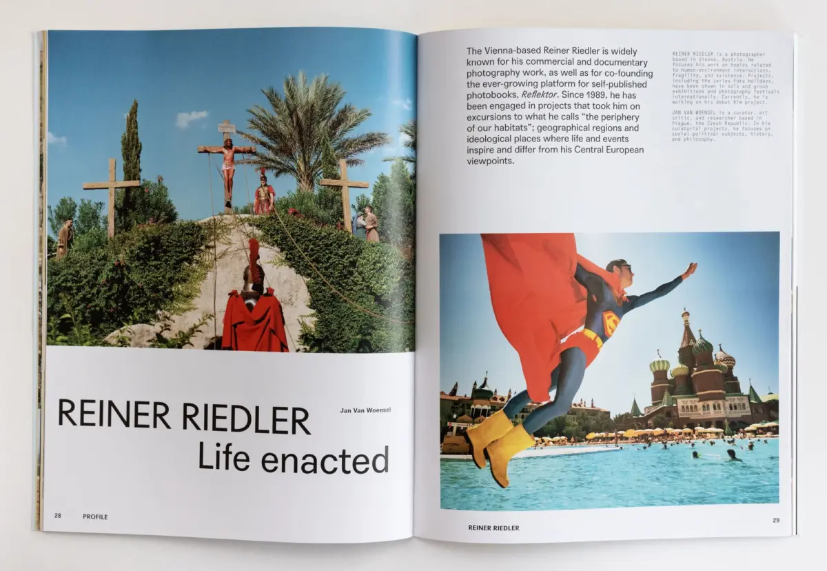 Open magazine spread showing outdoor hillside crucifixion tableau with palm trees and onlookers; adjacent page contains biography text.