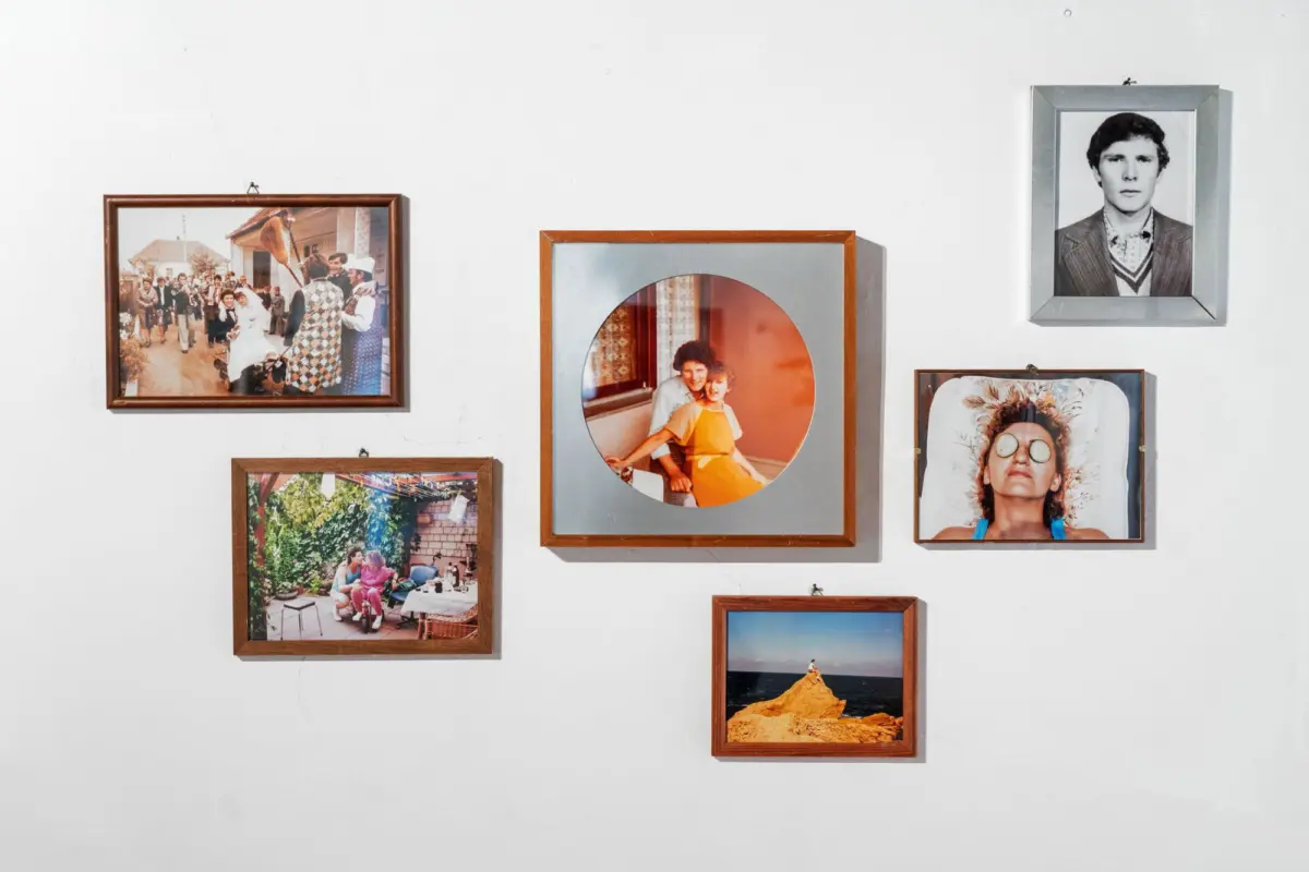 Wall of framed photos: wedding procession, circular orange-framed photo of a couple, black-and-white portrait of a man, and a woman with goggles.