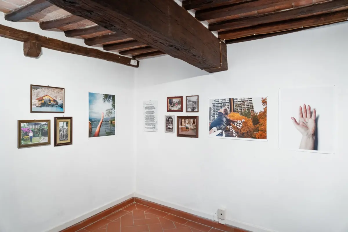 Exhibition corner with framed photographs on white walls under exposed timber ceiling beams.
