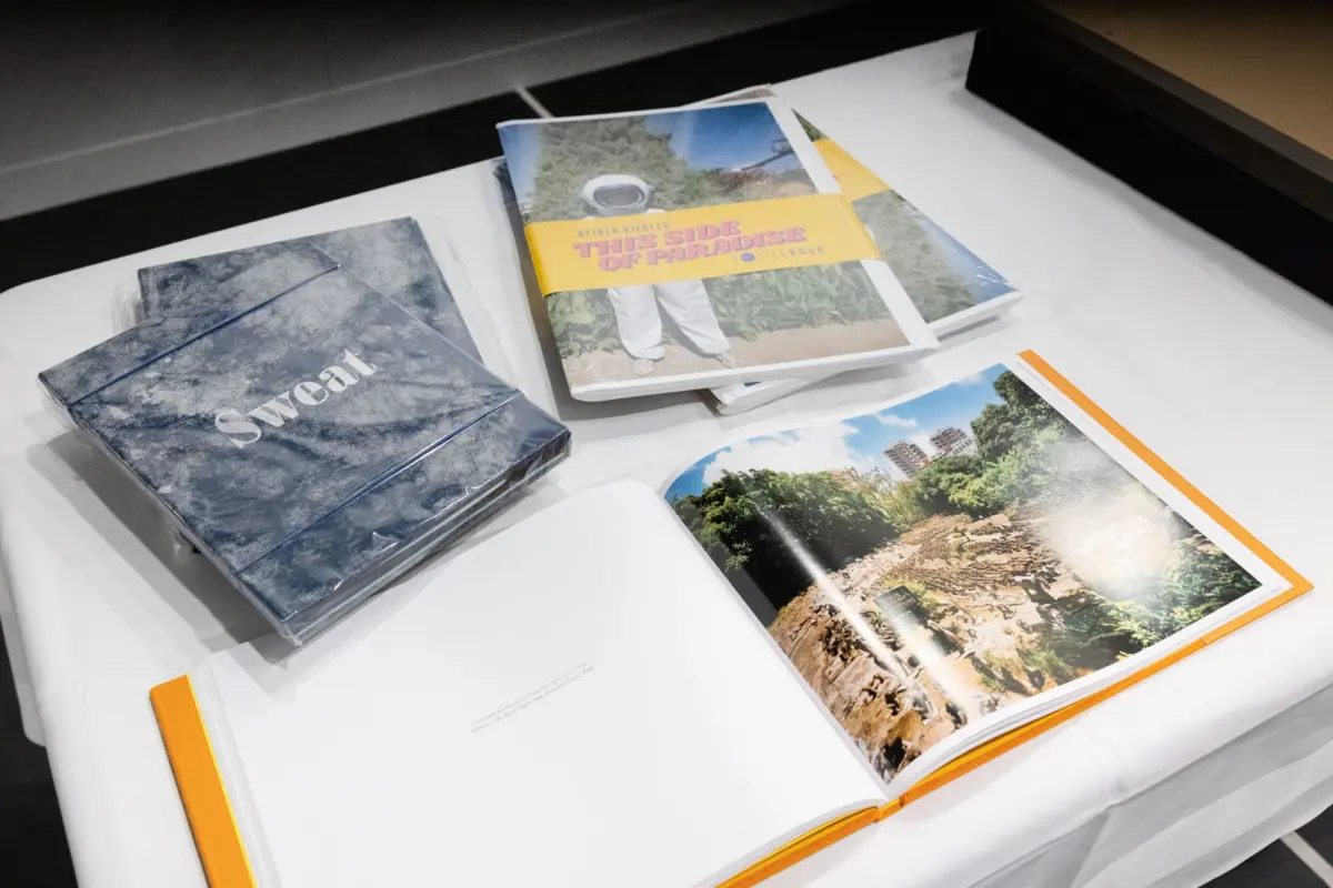Stack of coffee-table photo books on a white table; front cover reads 'This Side of Paradise' with a yellow band.