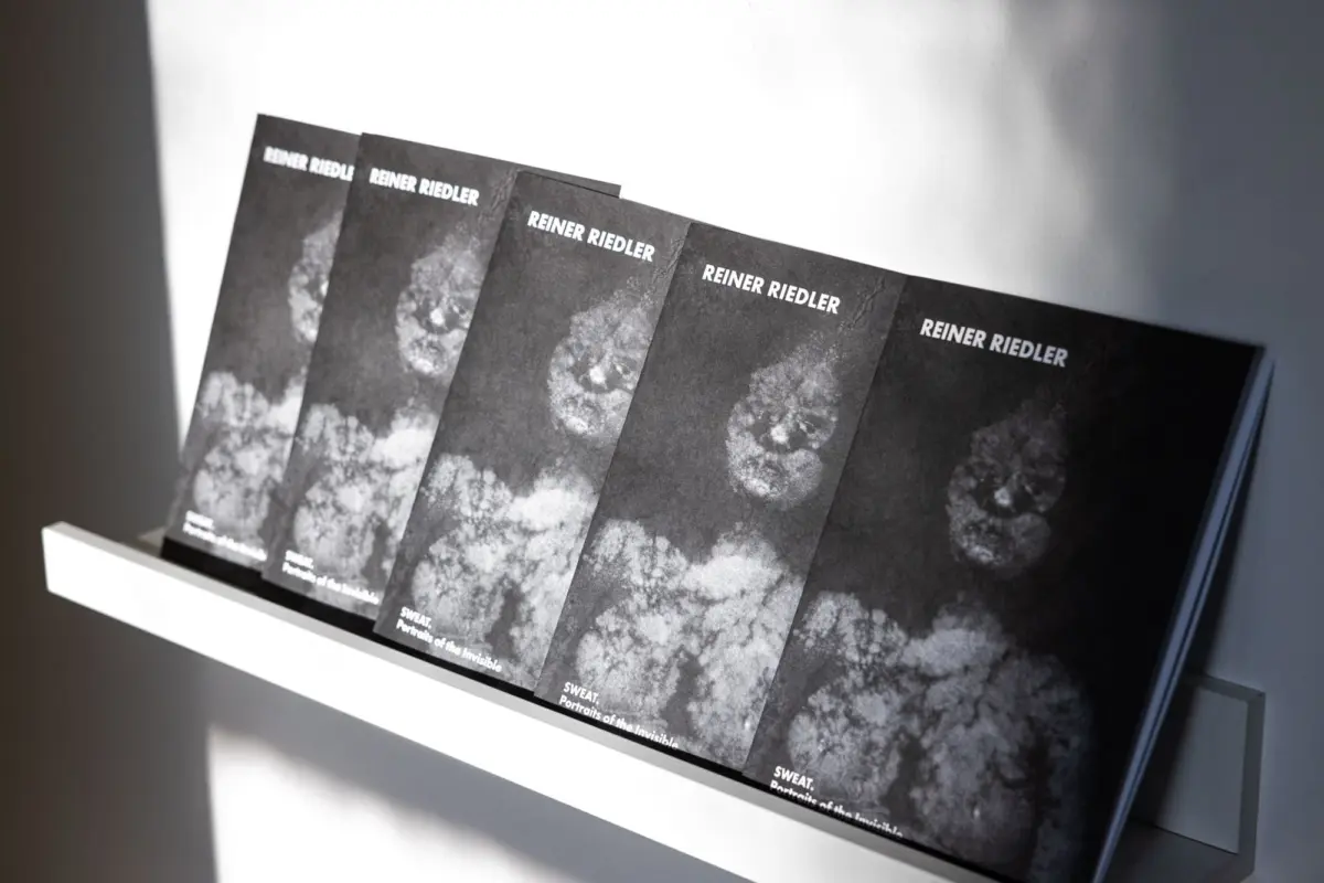 Row of black magazines titled REINER RIEDLER, fanned on a white shelf against a pale wall.