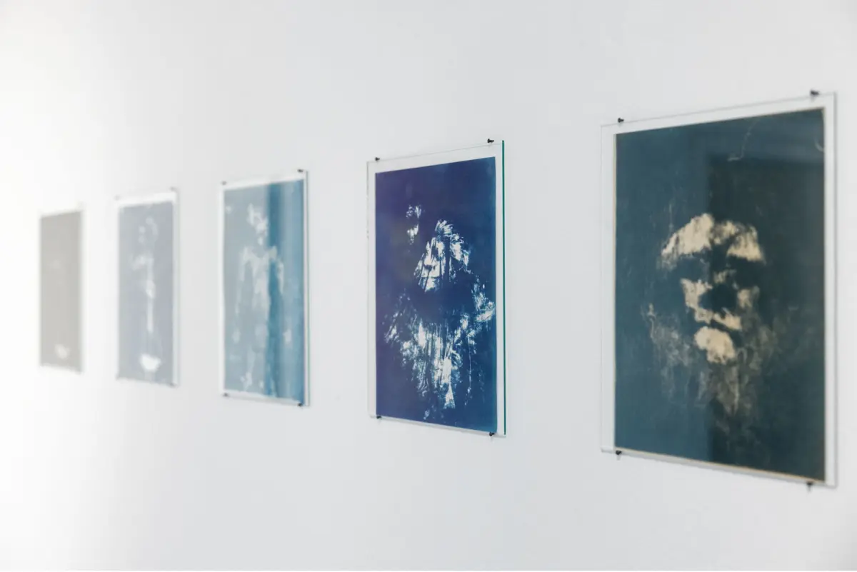 Blue-toned landscape photographs, framed and hung in a row on a white gallery wall.