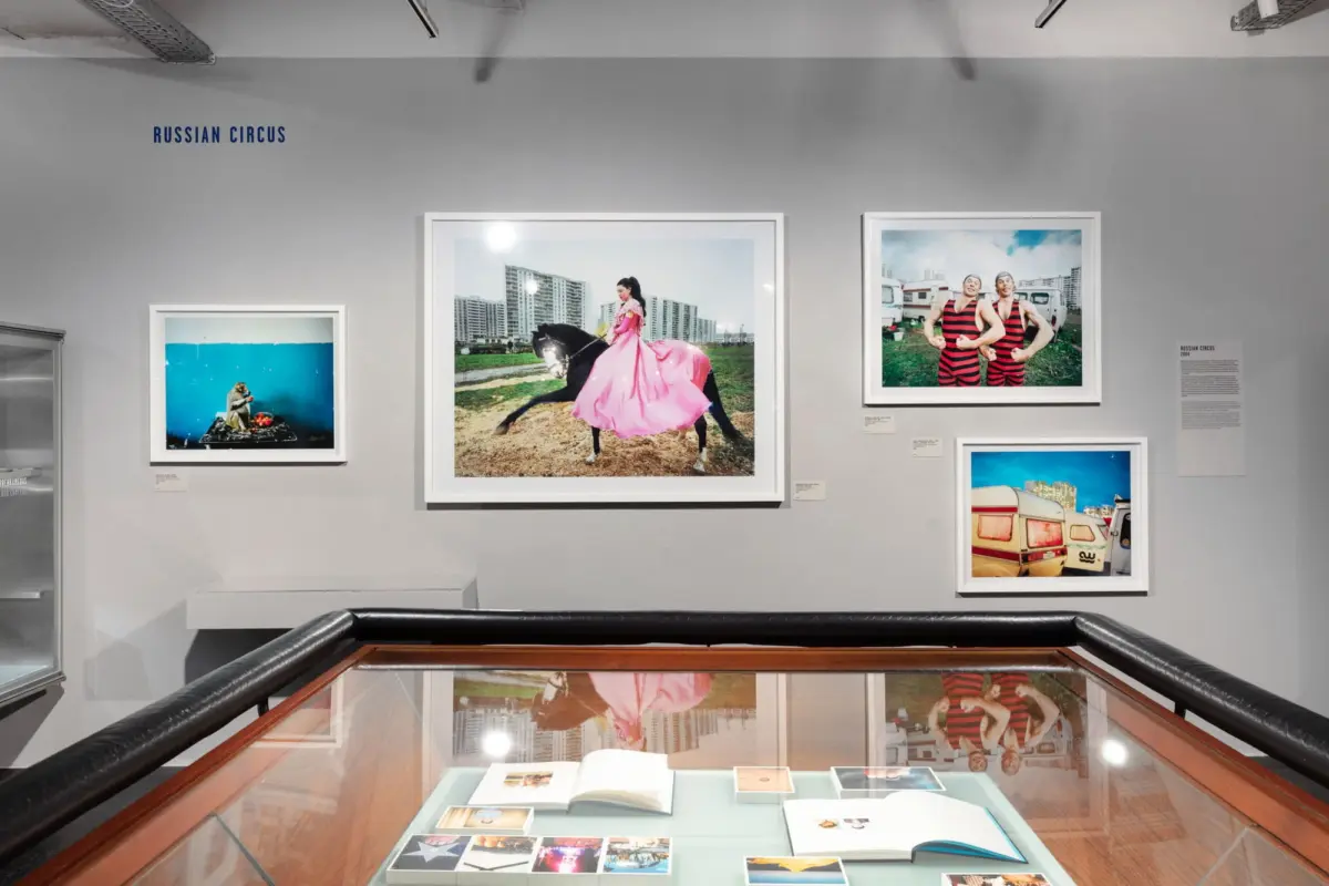 Gallery wall titled Russian Circus; central image shows a woman in pink riding a black horse in an urban setting; right image shows two men in striped outfits.