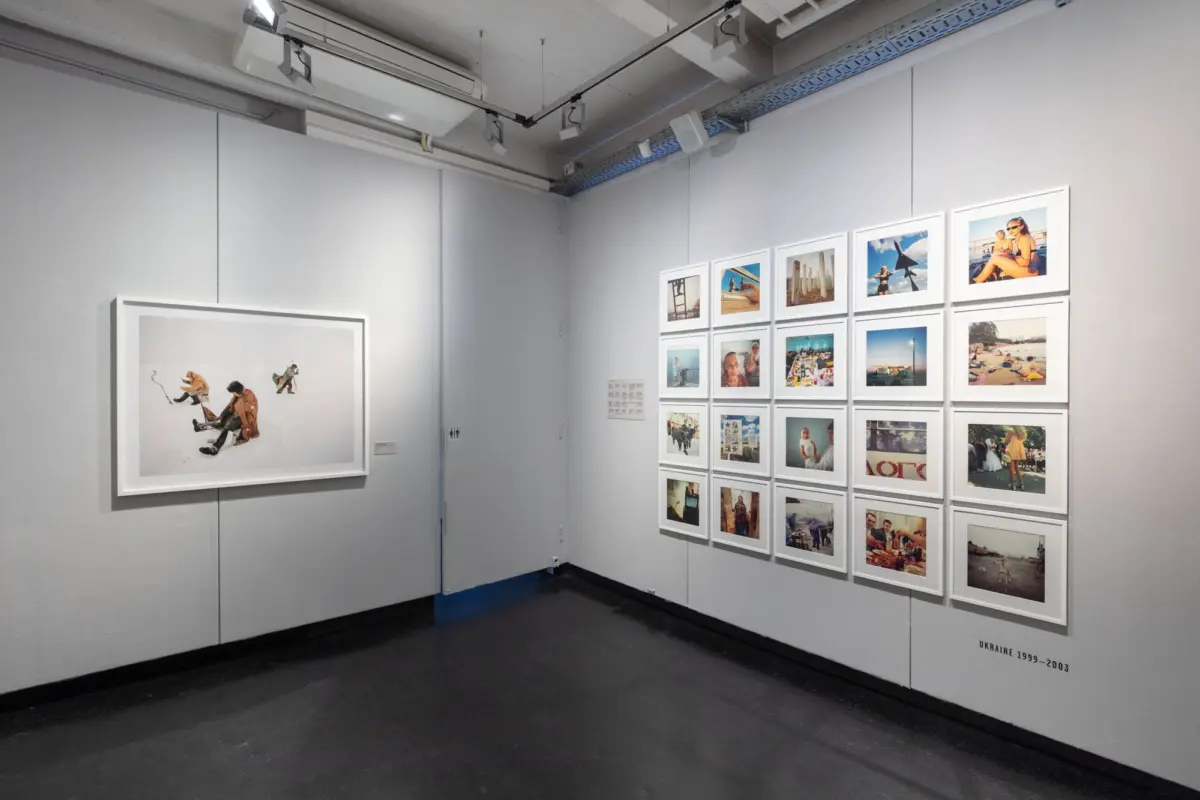 Gallery interior with a grid of small framed photographs on the right wall and a large framed snowy photograph on the left.