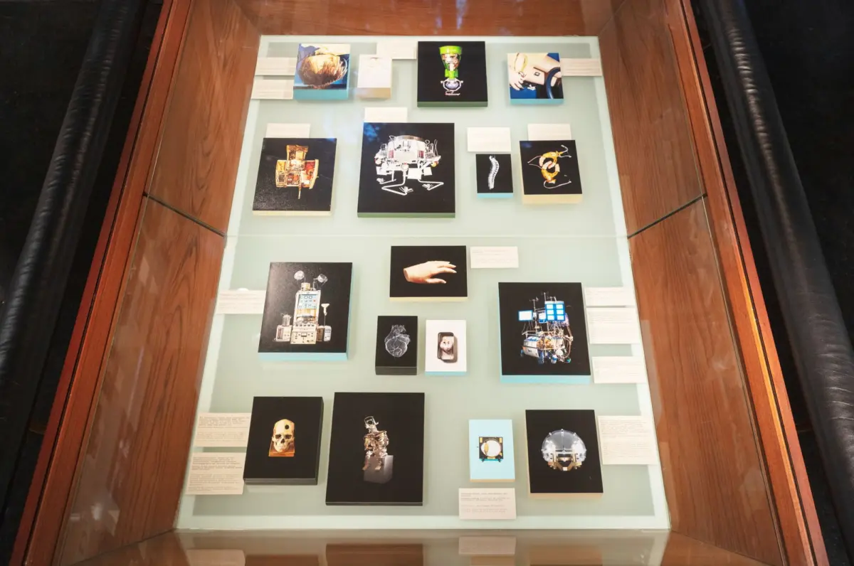 Museum display case with arranged panels and photographs of spacecraft, robots, and space gear on a pale blue background.