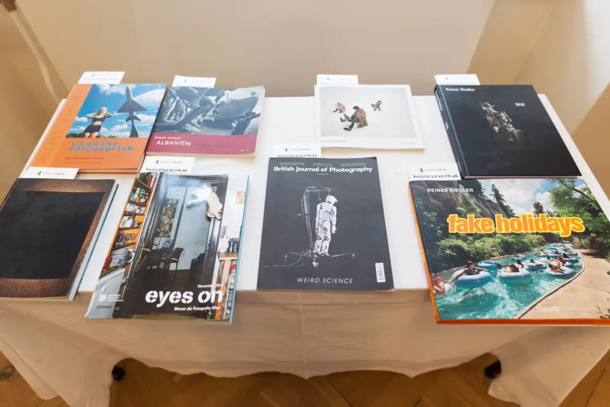 Photography books and magazines displayed on a table in an exhibit, including Fake Holidays and the British Journal of Photography.