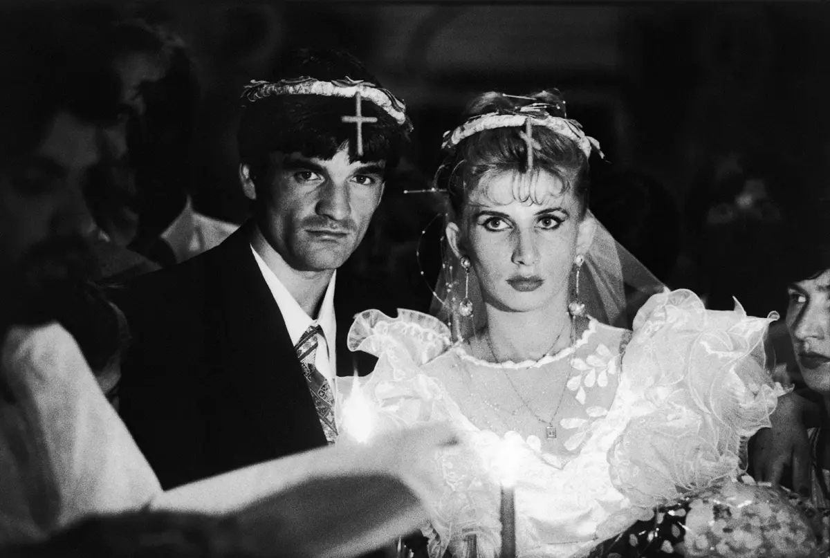 Bride in lace wedding gown and groom in suit standing at a candlelit wedding ceremony.
