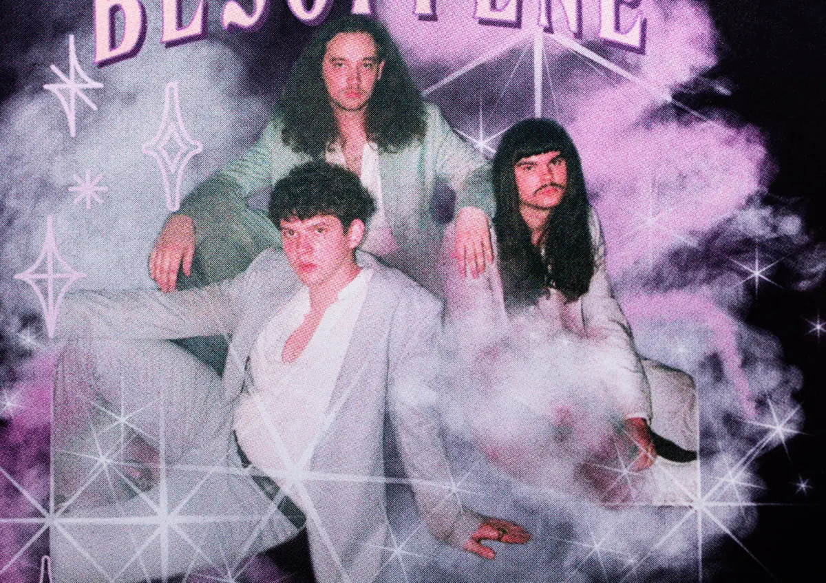 Three people in light-colored suits pose on a smoky, neon-lit stage with geometric star patterns and faint band text at the top.
