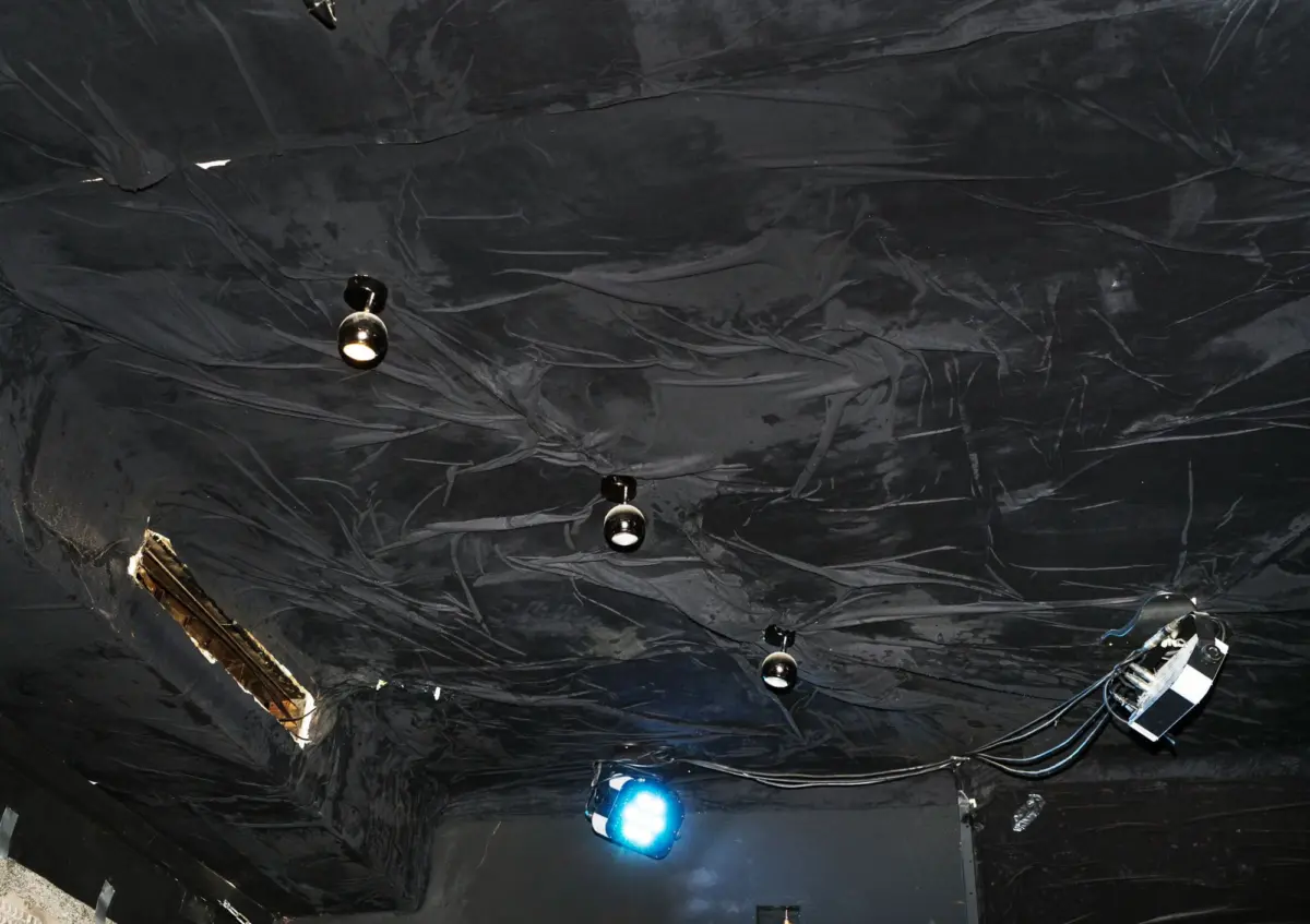 Black ceiling with hanging spherical stage lights and cables in a theater setting.