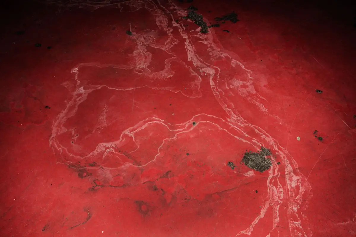 Red concrete floor with white vein patterns and dark stains.