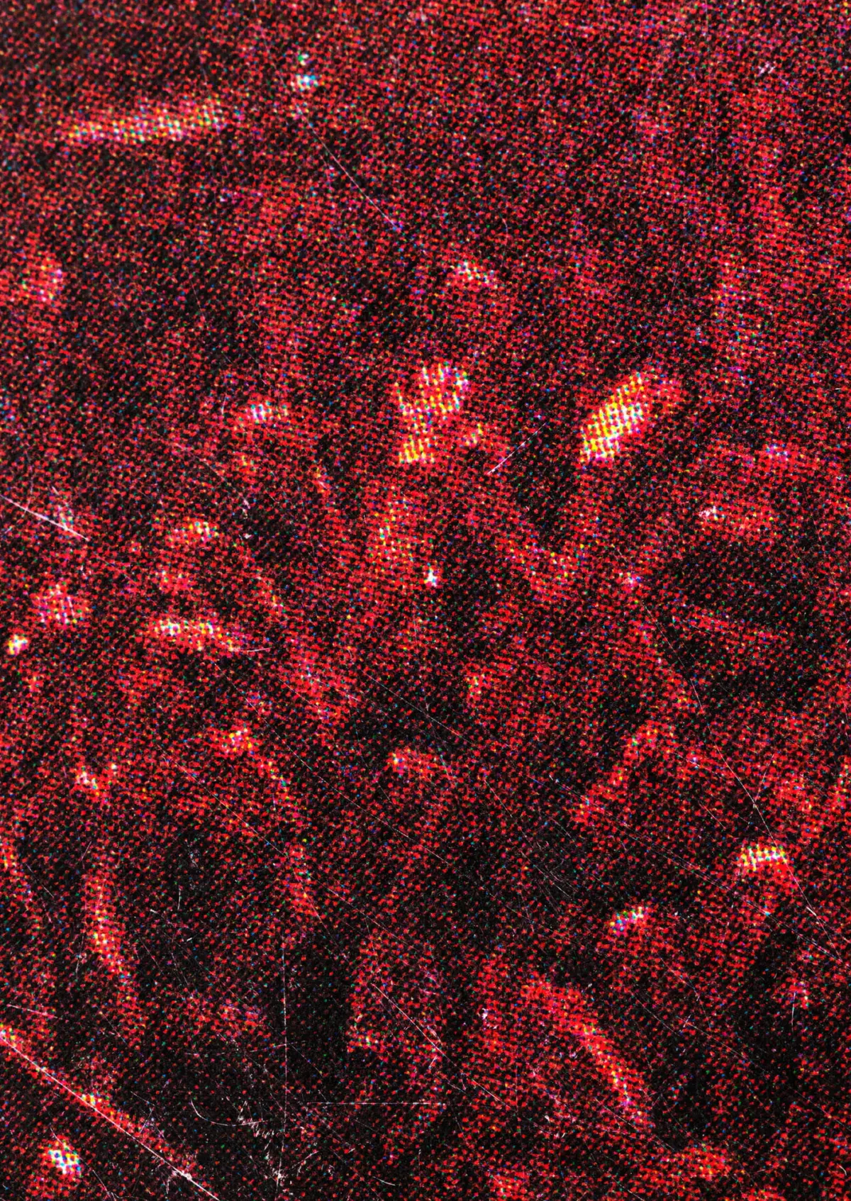 Macro shot of red glitter flecks on a dark textured surface.